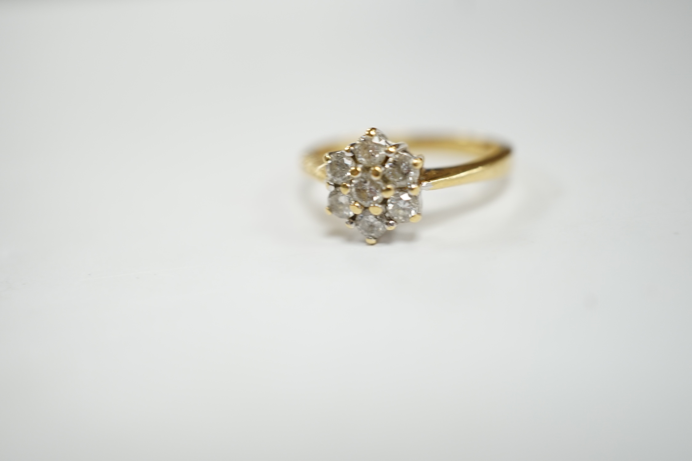 A modern 18ct gold and seven stone diamond cluster set flower head ring, size N, gross weight 3.6 grams.